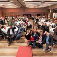 Asistentes a la gala Premios AICE 2025 haciendo el símbolo del Implante Coclear.